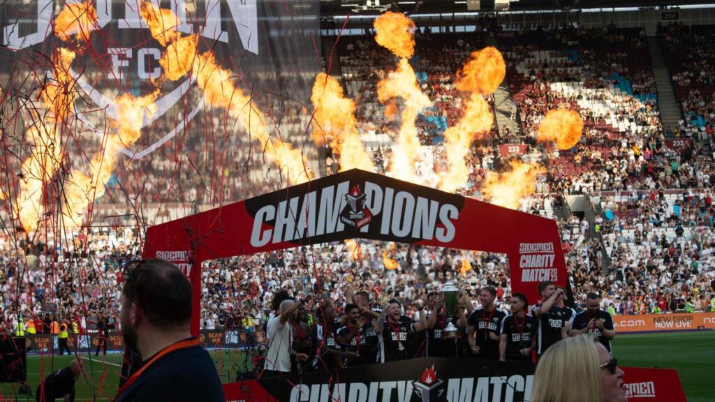 Sidemen FC celebrating win with trophy lift and pyrotechnics.