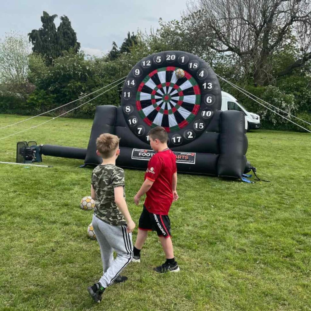 Children playing football dartboard hire outside.