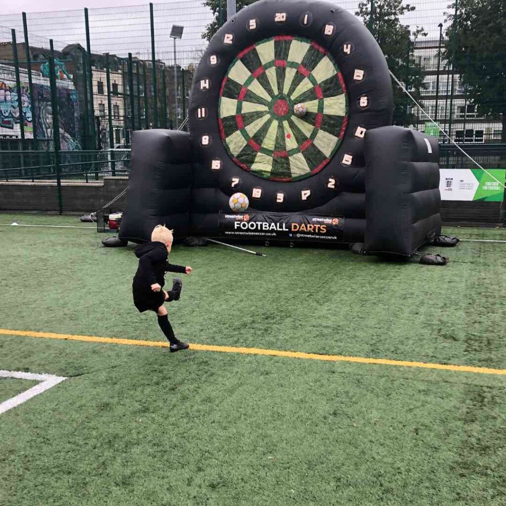 Children playing giant football inflatable darts.