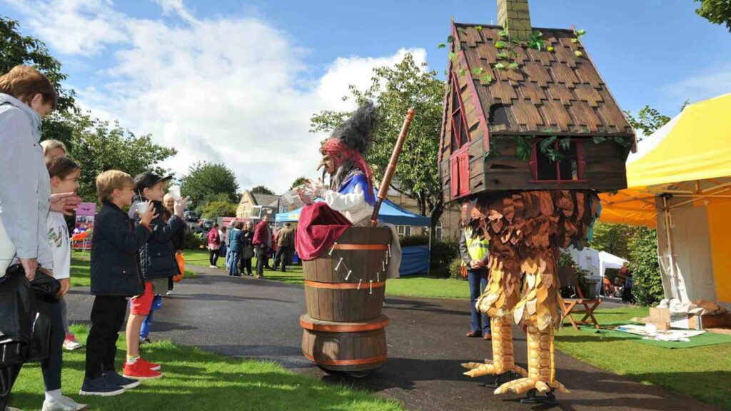 Old crone themed walkabout act with ramshackle cottage on chicken legs for street theatre.