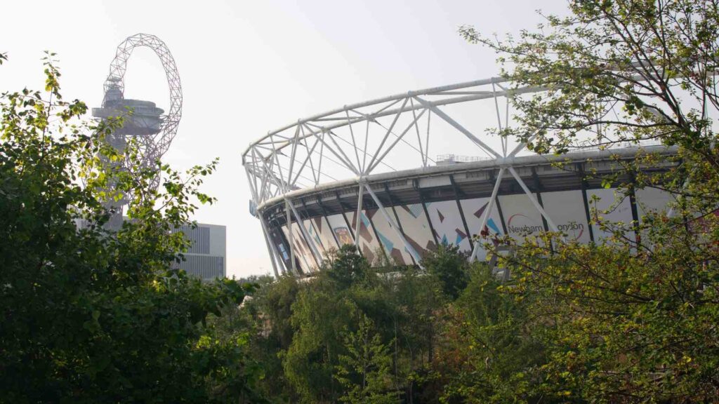 Exterior of the Queen Elizabeth Olympic Park London Stadium with ArcelorMittal Orbit in the background.