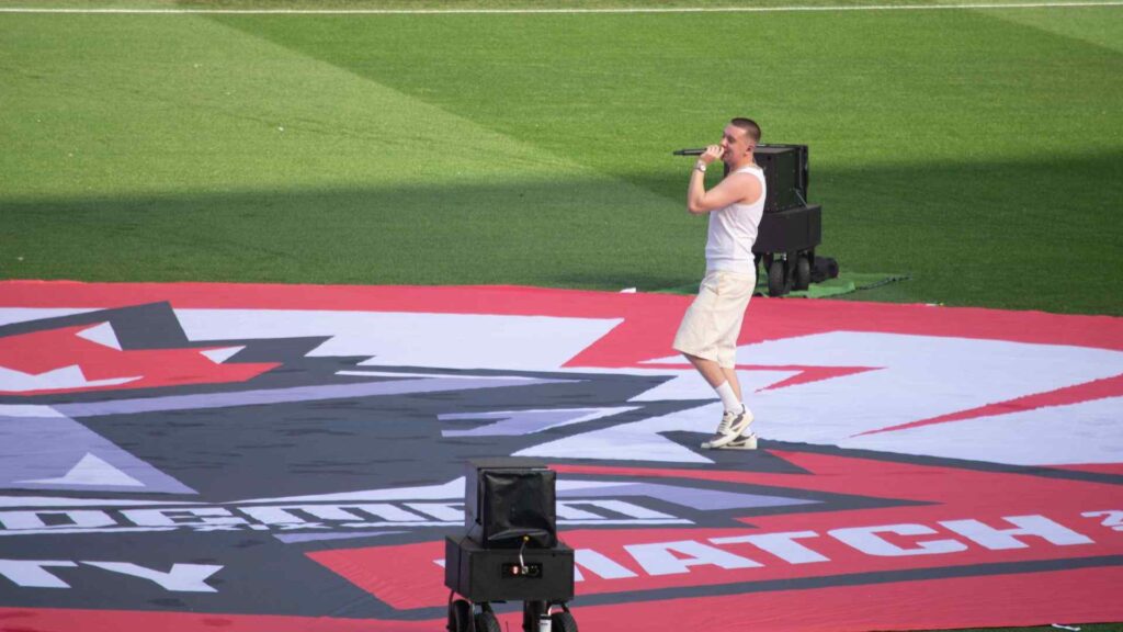 Aitch on the centre circle performing to the Sidemen Charity Match fans.