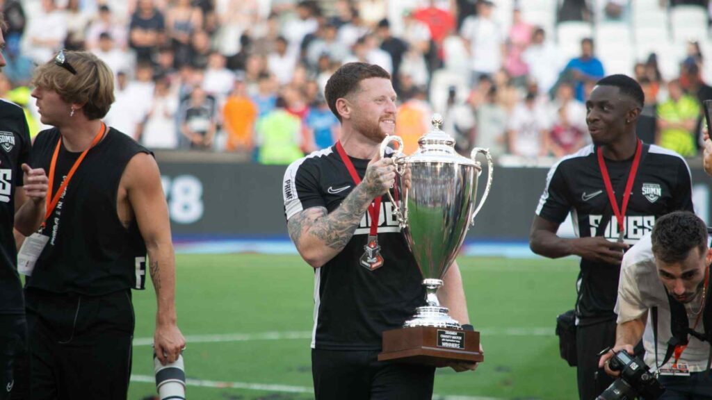 Ethan holding the winners trophy on pitch.