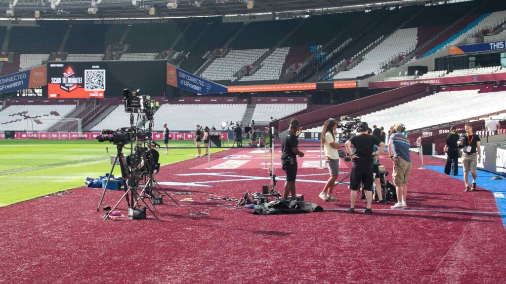 Staff pitch side at the Sidemen 2023 Charity Match setting up production equipment for the livestream.
