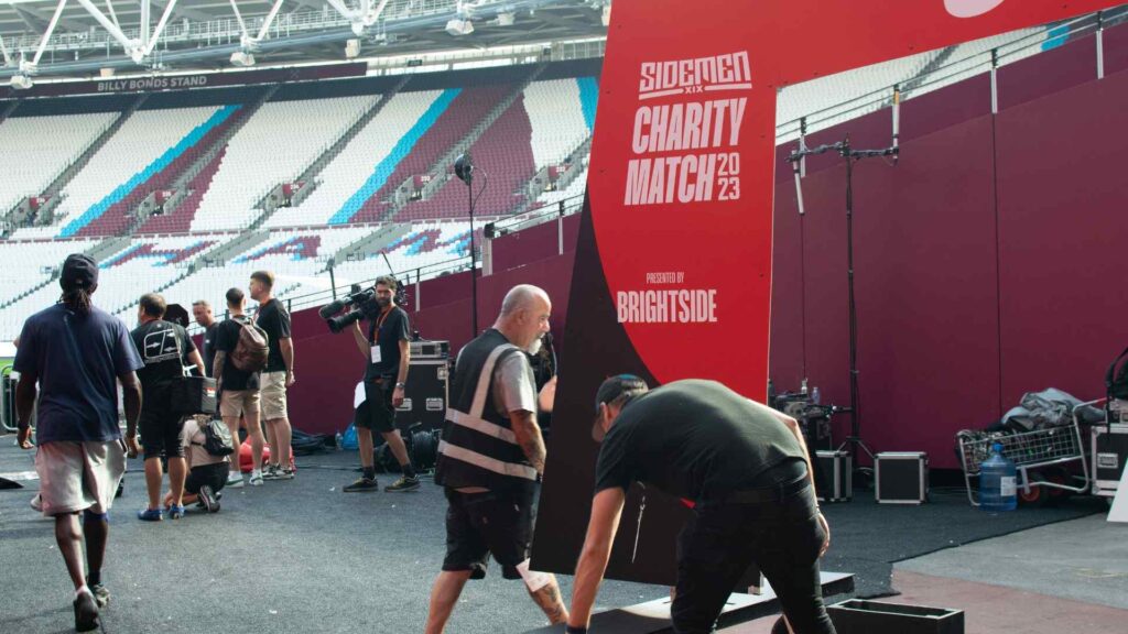 Sidemen Charity Match 2023 team running through rehearsal of setting up awards facade in stadium entrance.
