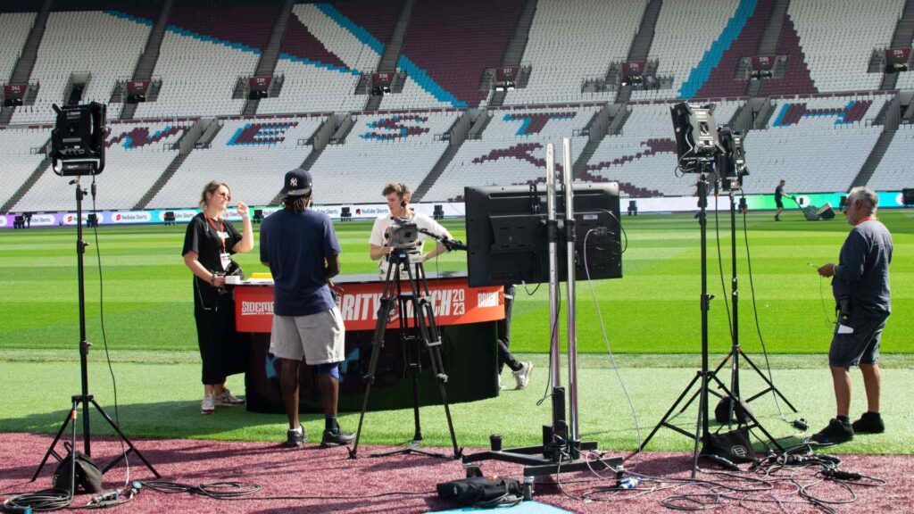 Team setting up and testing production equipment for pundit desk at 2023 Sidemen Charity Match.