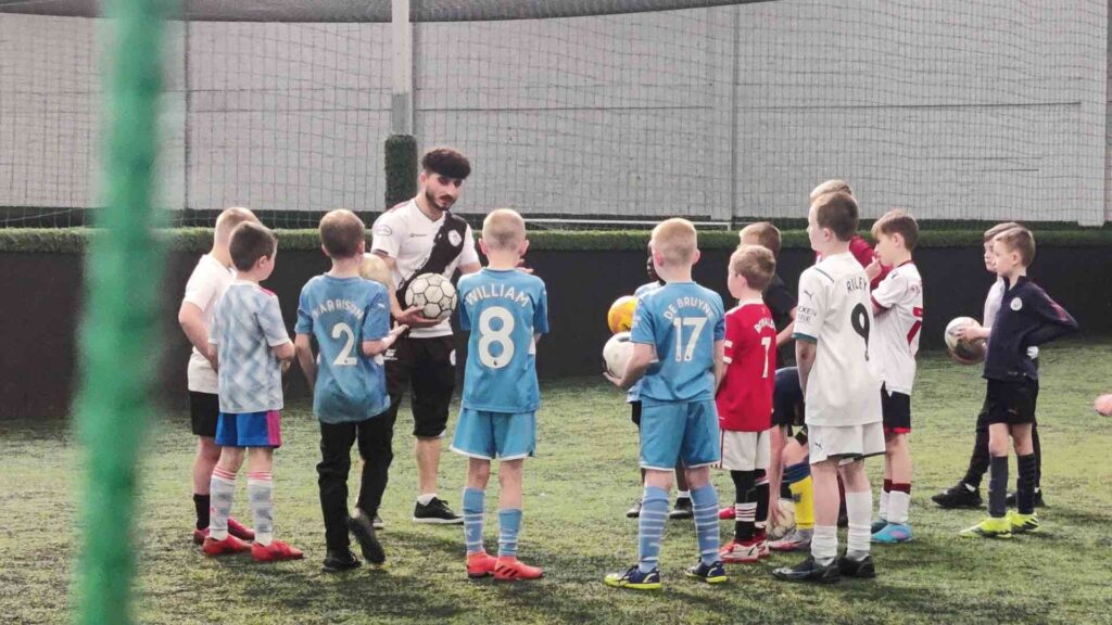 Football freestyler working with children on their football techniques.