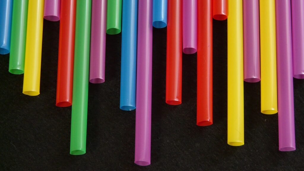 Collection of single use plastic straws in multiple bright colours.