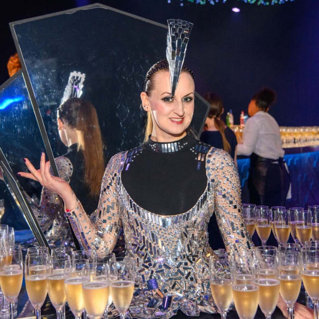 Luxury champagne table server in black and silver outfit.