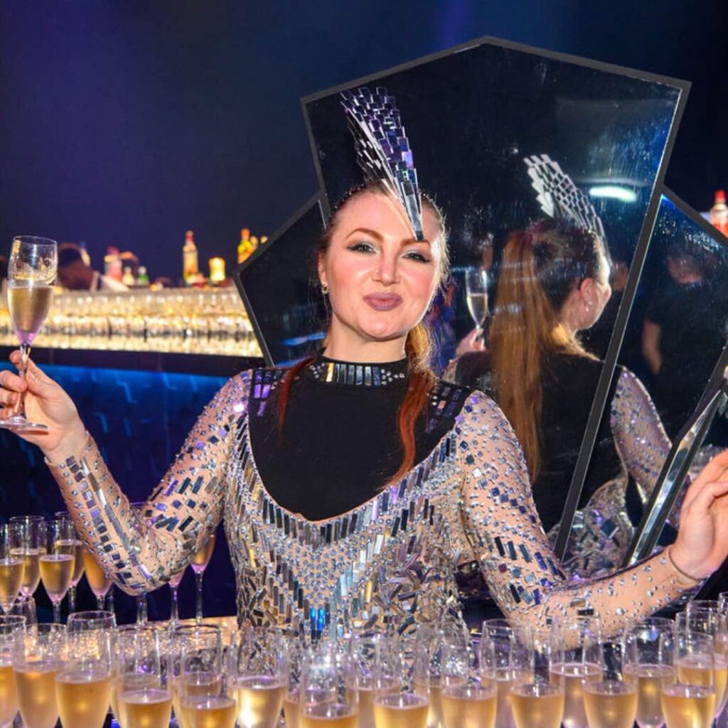 Formal champagne skirt server in black and silver outfit at corporate event.