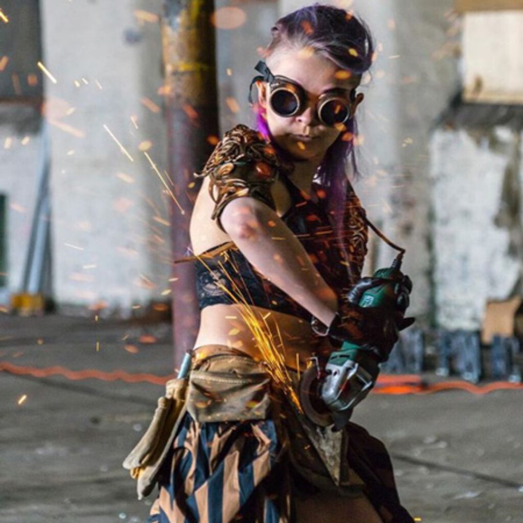 Steampunk woman with chainsaw making sparks fly.
