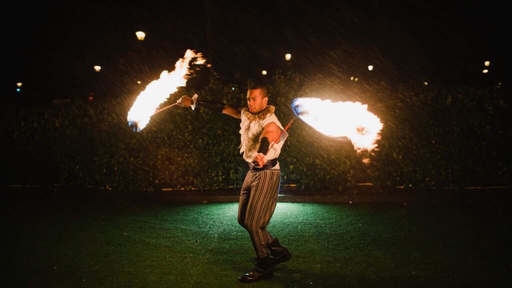 Fire performer at a circus themed party outdoors at night.