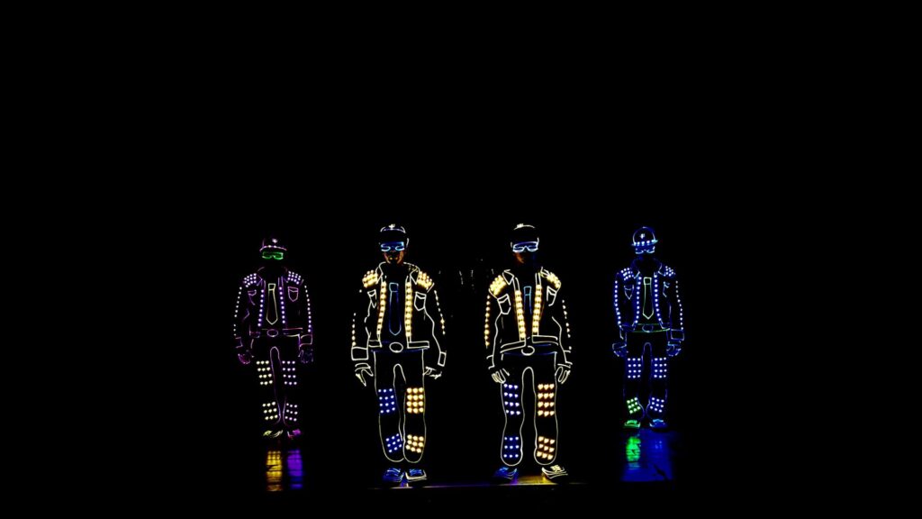 Four LED circus performers wearing multicoloured light up suits