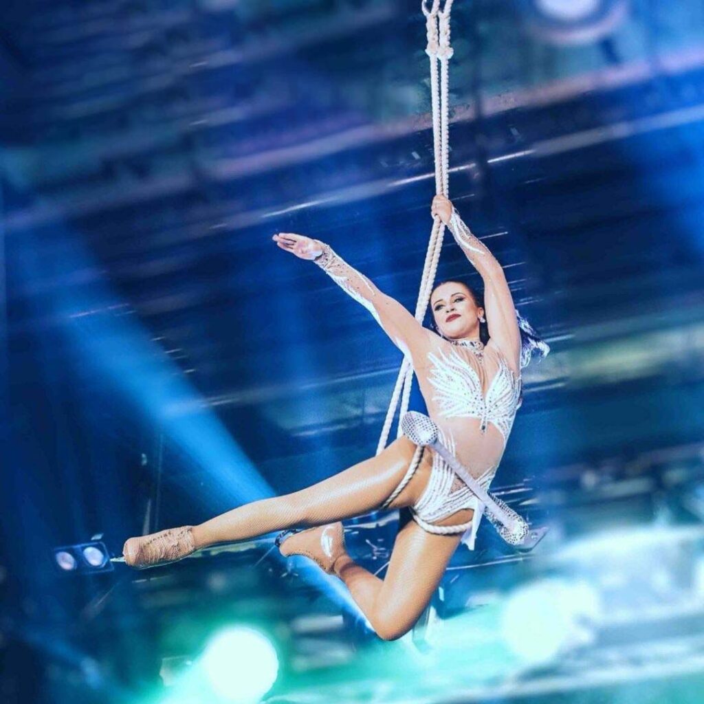 Trapezium ice skating act doing aerial trick using rope.
