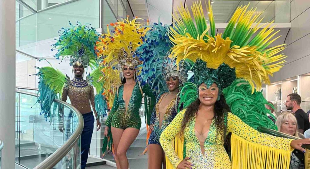 Carnival dancers in vibrant yellow and green costumes posing on stairs at McLaren around the world themed corporate event
