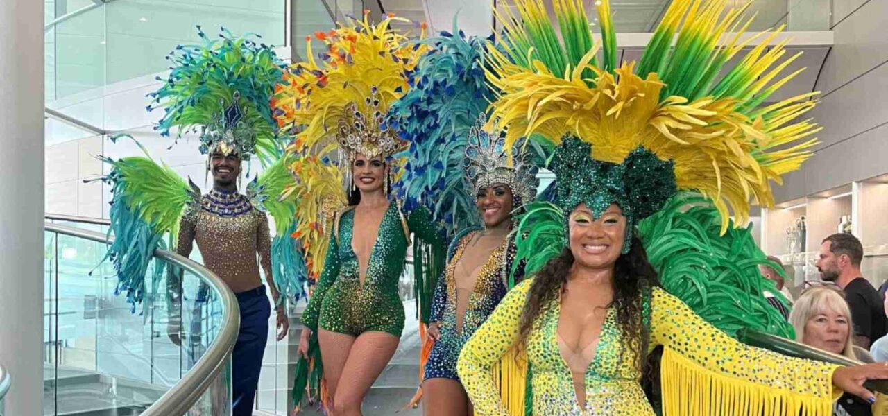 Carnival dancers in vibrant yellow and green costumes posing on stairs at McLaren around the world themed corporate event