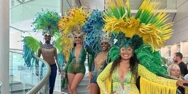 Carnival dancers in vibrant yellow and green costumes posing on stairs at McLaren around the world themed corporate event