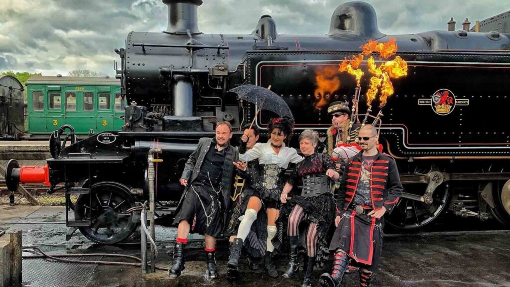 bagpipe band for hire in front of steam train.