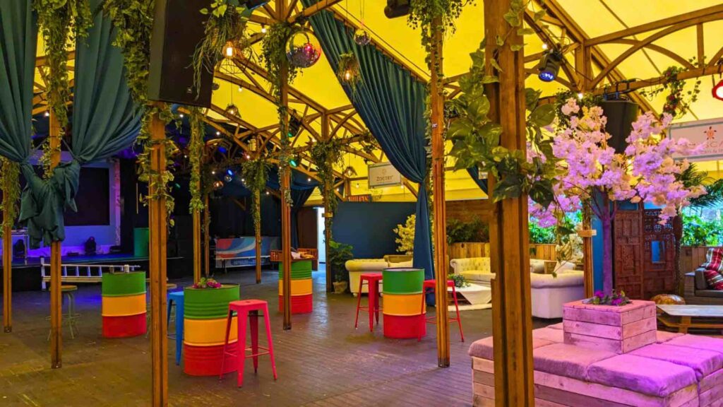 Vibrant indoor festival themed corporate event with barrel furniture and stools with pallet furniture.