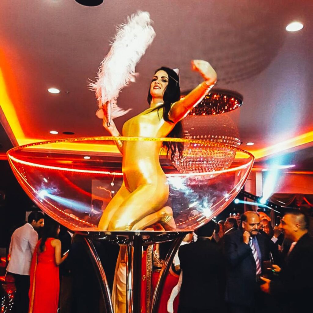 A golden girl dancer from James Bond Theme inside a giant martini glass prop.