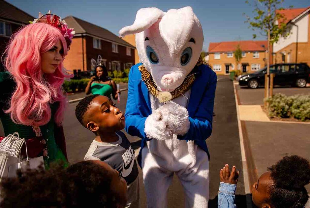 Easter bunny character and fairy interacting with children at corporate community event.