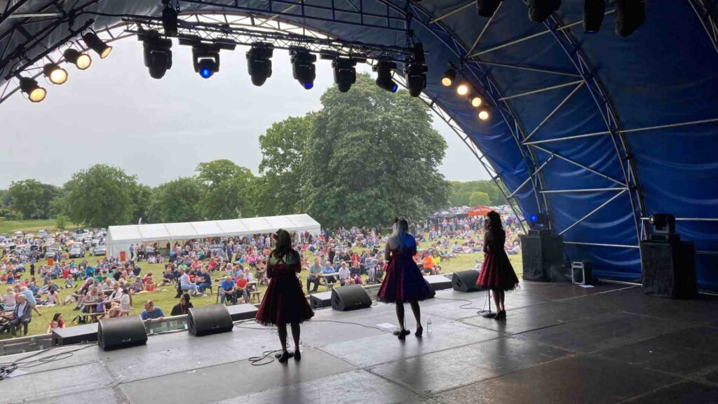 3 1940s style singers performing on stage to audience at community event.