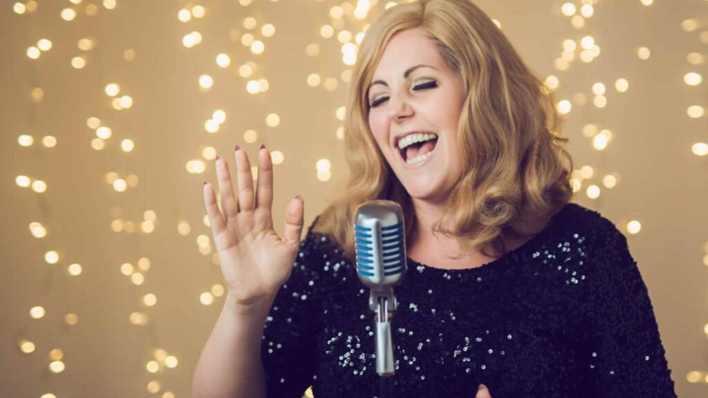 Famous singing tribute adele act in a black outfit with a microphone performing live.