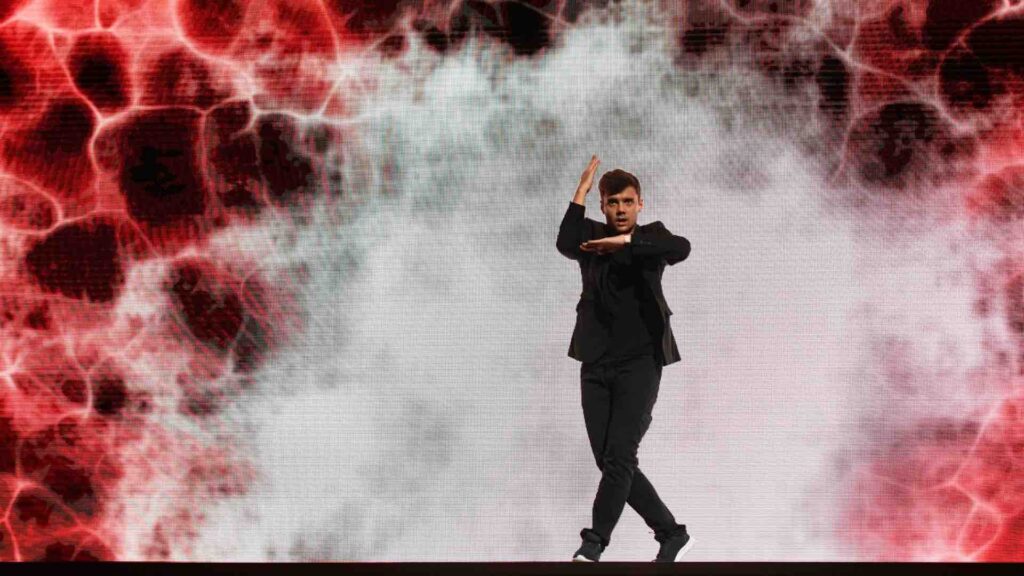 Famous hip hop champion artist on stage performing in front of 3d projection at a gala event.