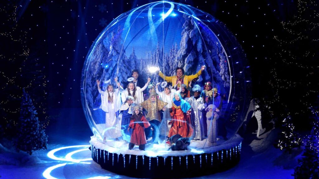 People posing inside giant snow globe at winter wonderland themed event.