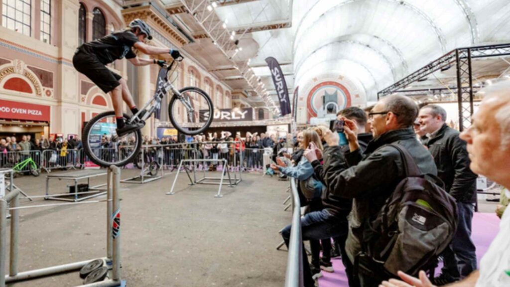 A mountain bike stunt show featuring balance stunts being performed at an exhibition