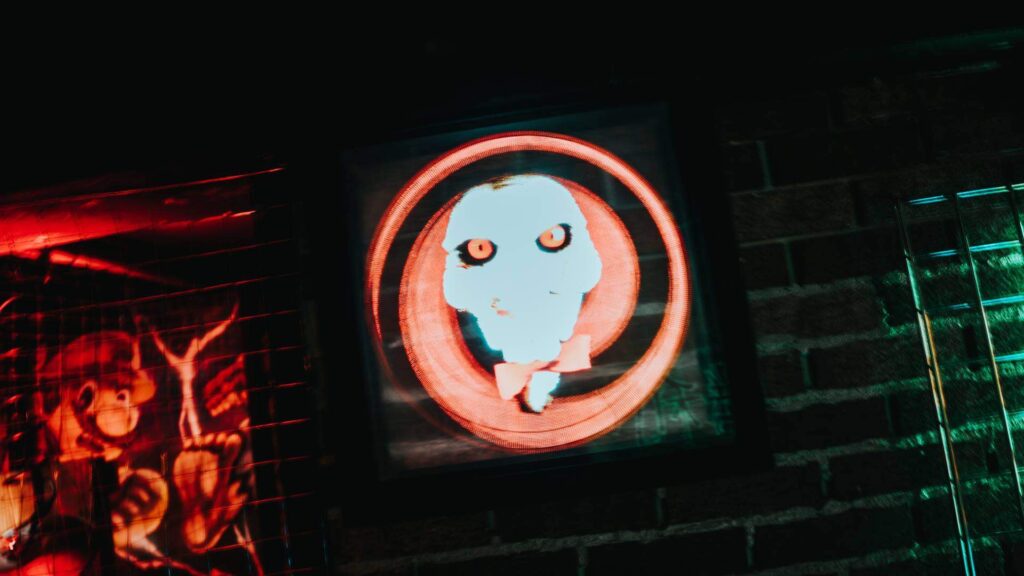 Billy the puppet from SAW movie franchise illuminated logo for Halloween event planners.