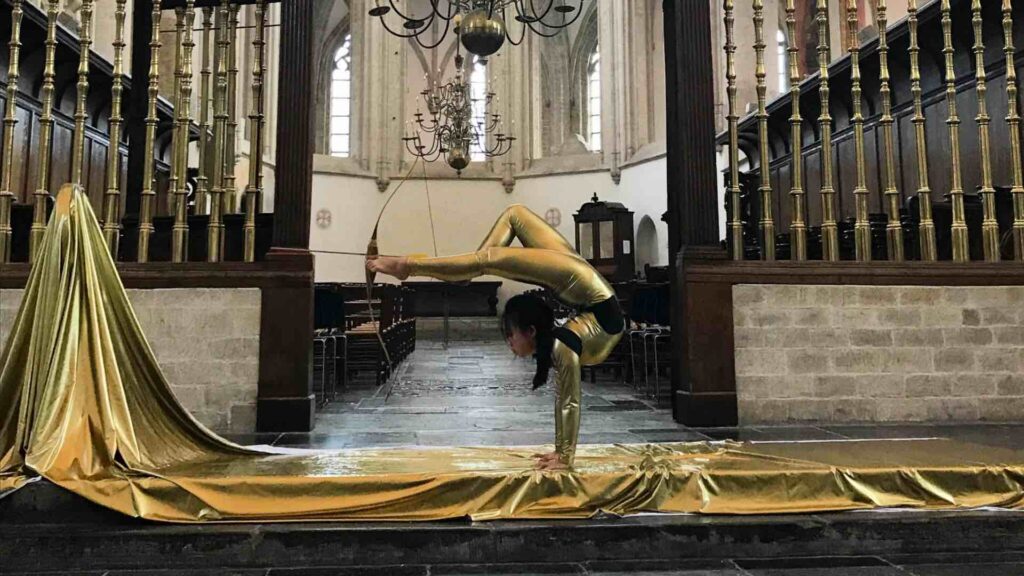 Golden bow and arrow contortion act shooting arrow at sporting event.
