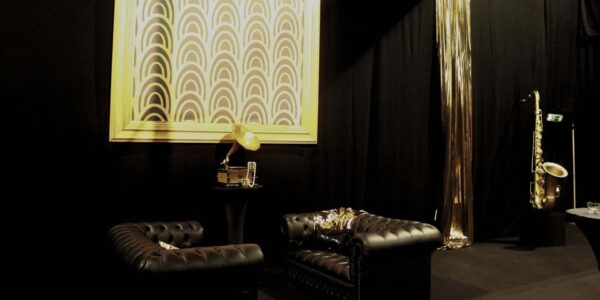 Opulent Gatsby themed party space with 1920s theme decor such as leather furniture and art deco wall decor.