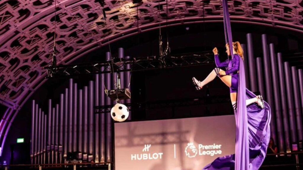 An aerialist dressed in a football kit performing a Football Themed Aerial Skills show.