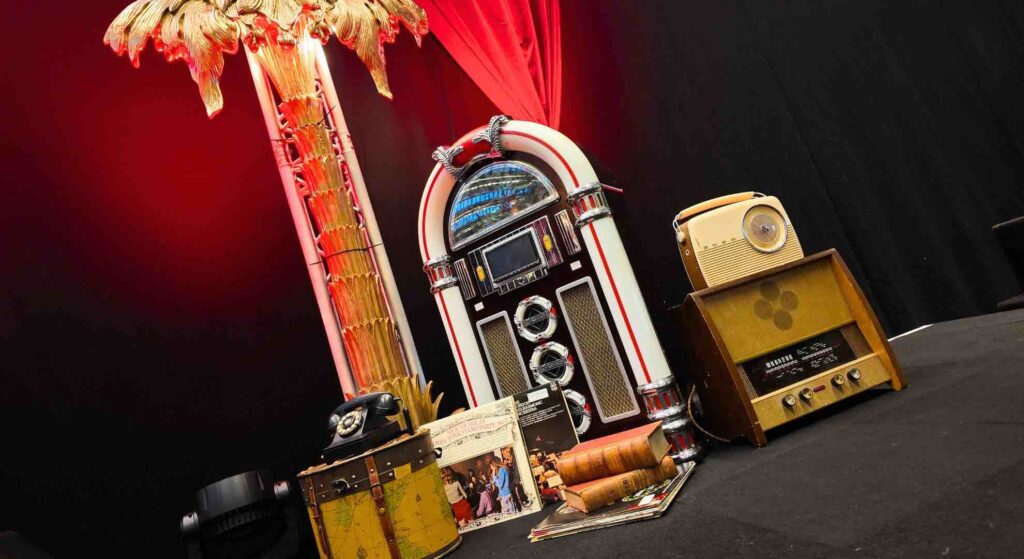 Old music player with palm tree prop and musical 1920s theme styling used to transform a stage for a 1920s theme event.