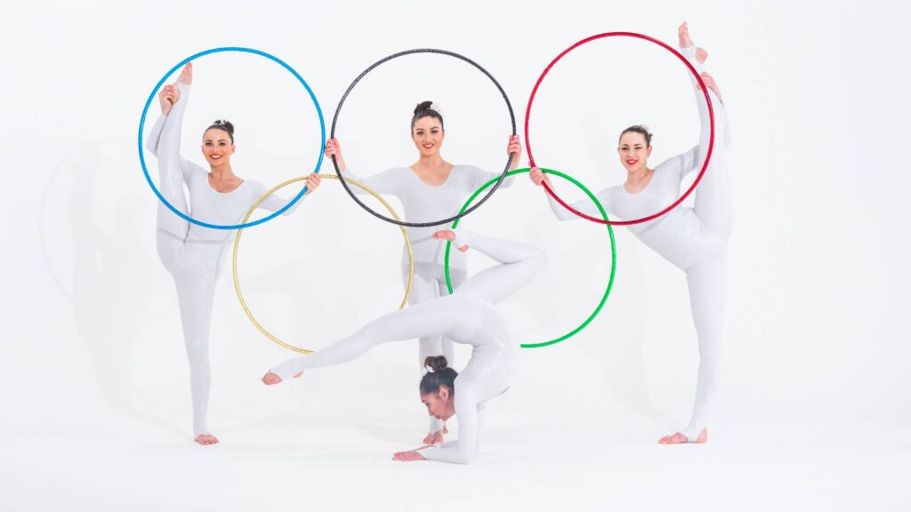 Olympic themed aerialists holding five gold rings from olympics as olympic themed entertainment for sports event.