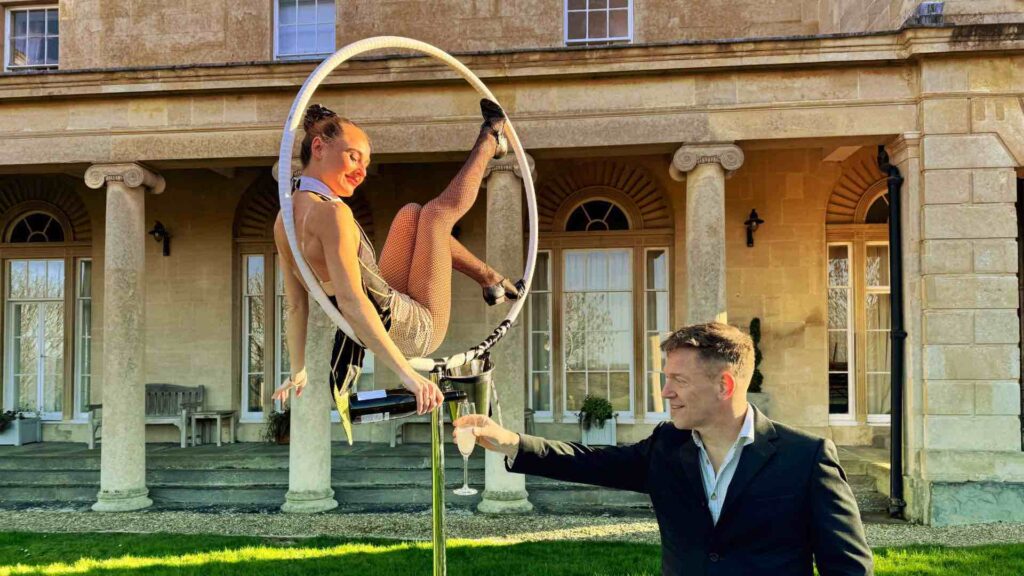 Paris themed aerialist in a hoop pouring champagne to a guest at a lavish event.