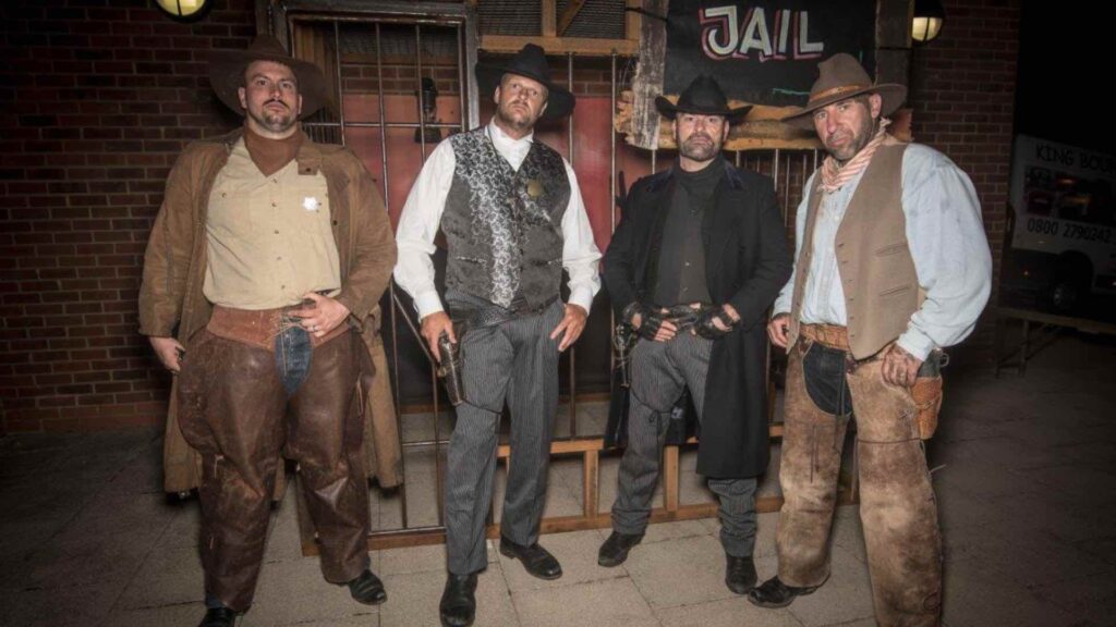 Group photo of wild west performers in themed event set jail cell.