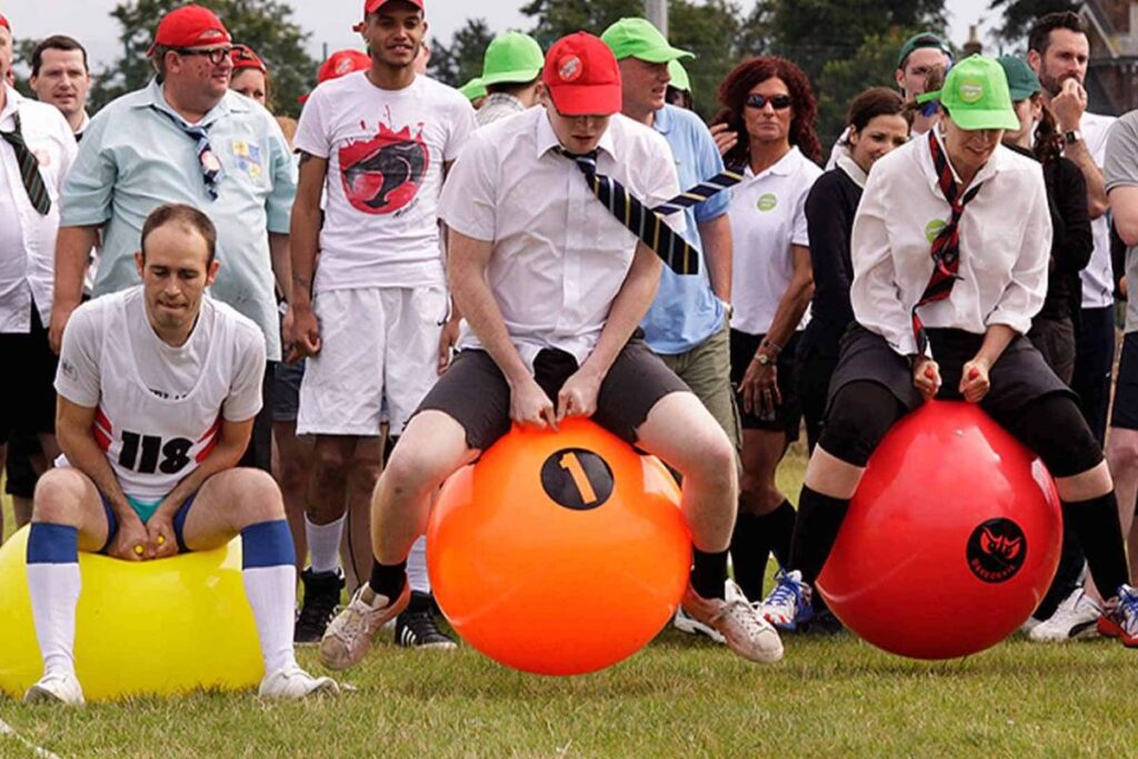 Corporate sports day employees racing on bounce hoppers.