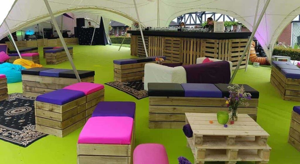 Eco friendly pallet furniture layout with seating, bar and coffee table for a corporate event.