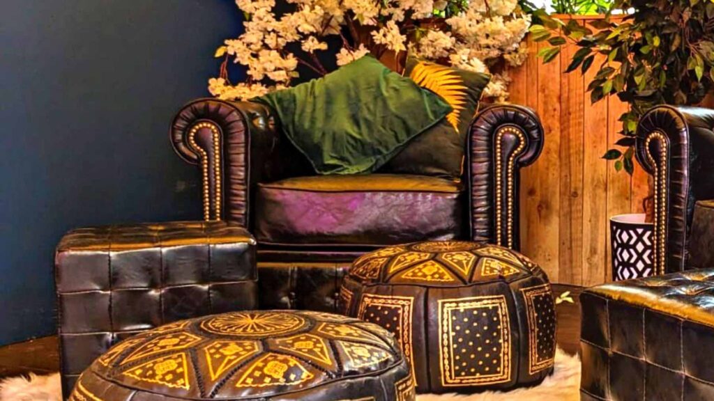 Brown leather event furniture with gold accents including armchair and footstall.