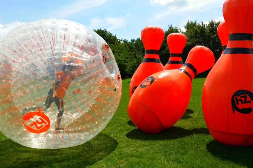 Zorb bowling for outdoor corporate events with orange ten pins and human in zorb ball.