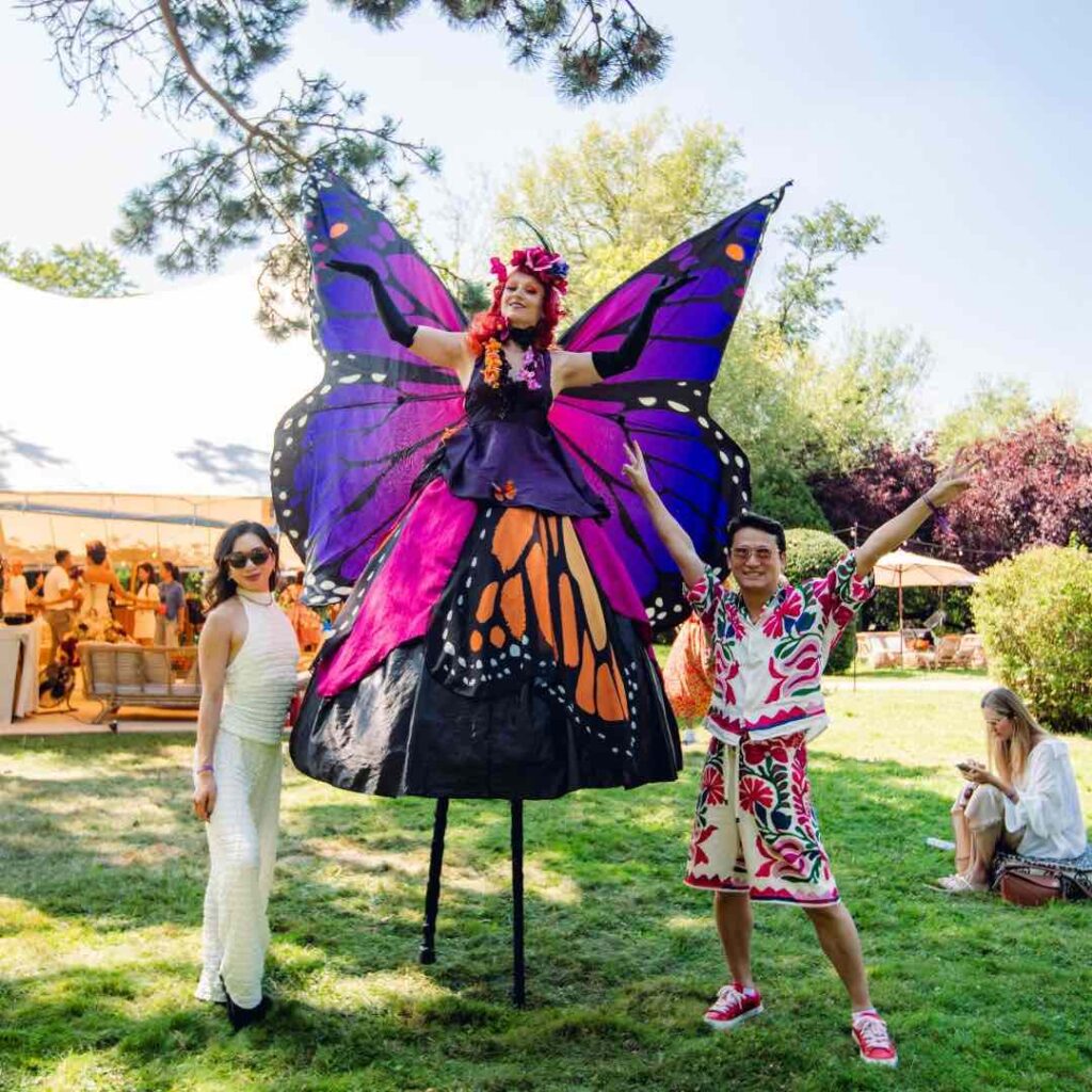Butterfly stilt walker posing with guests for photos at corporate festival event.