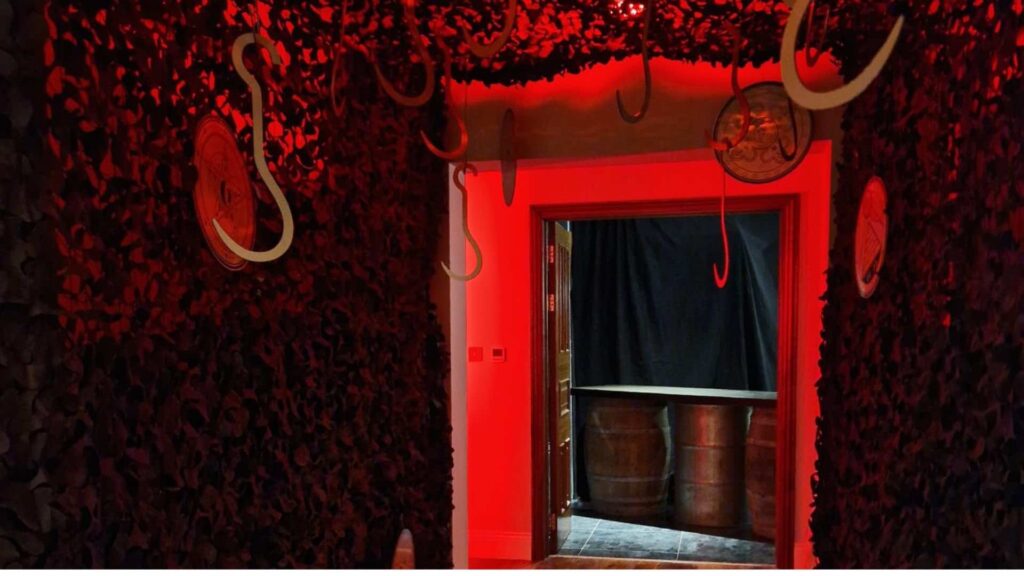 Entryway to butchers slaughterhouse with hanging hooks and blood red lighting.