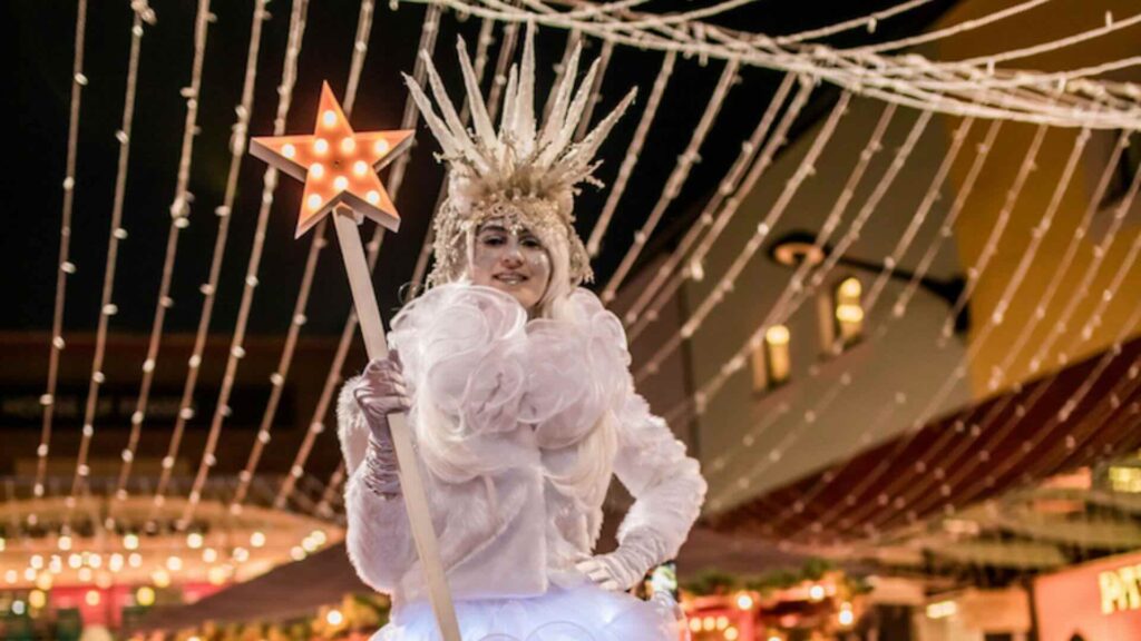 Ice Queen Stilt Walker posing with a magic wand