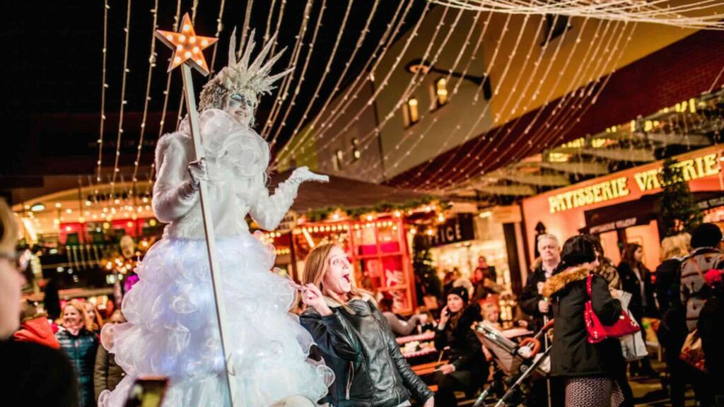 Ice Queen Stilt Walker towering above crowds with a magic wand.