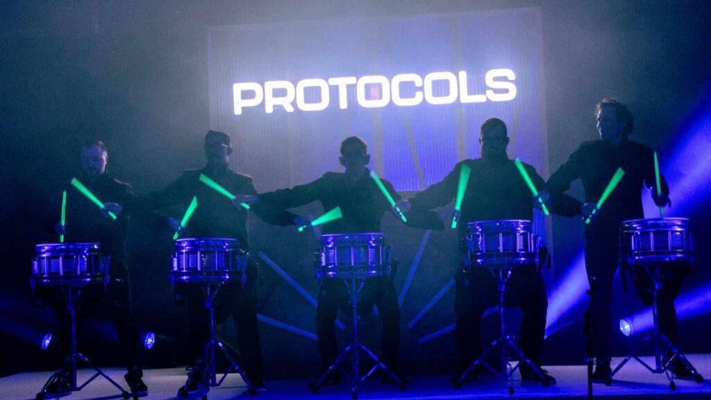 LED drummers with green glow sticks on protocols stage at corporate festival event.