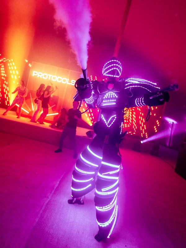 Pink LED dancer at corporate festival event firing smoke into audience.
