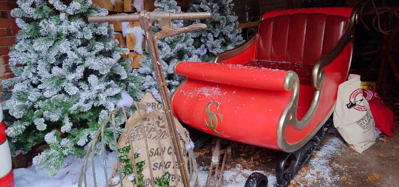 Santas sleigh sat outside with trees and props for grotto.,