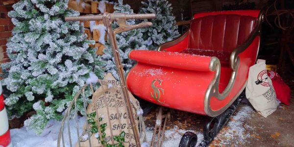 Santas sleigh sat outside with trees and props for grotto.,